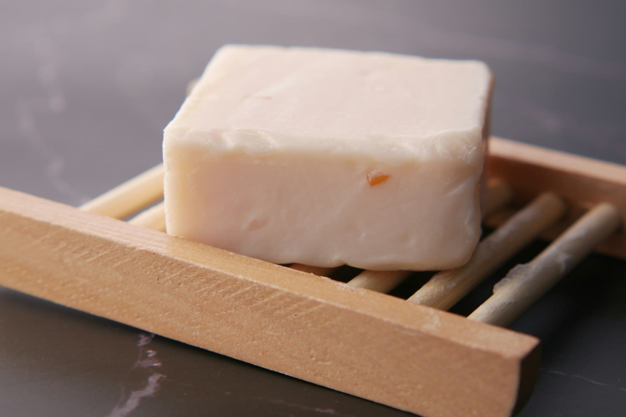 A bar of natural soap on a wooden soap dish
