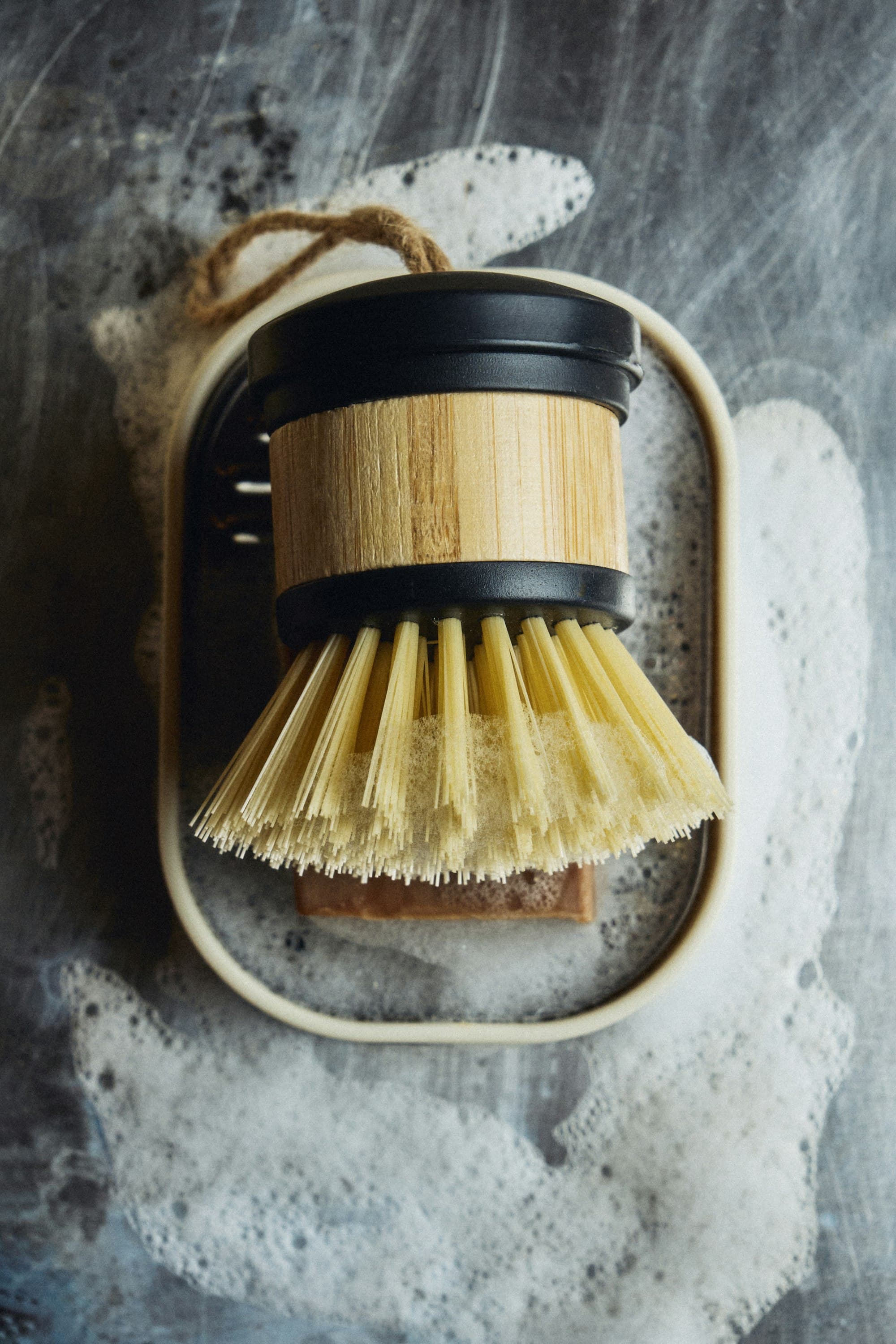 A wooden dish brush with natural bristles and soap suds