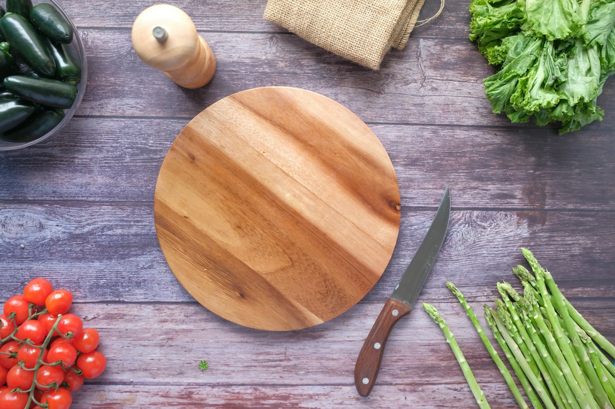 A round wooden chopping board with fresh vegetables